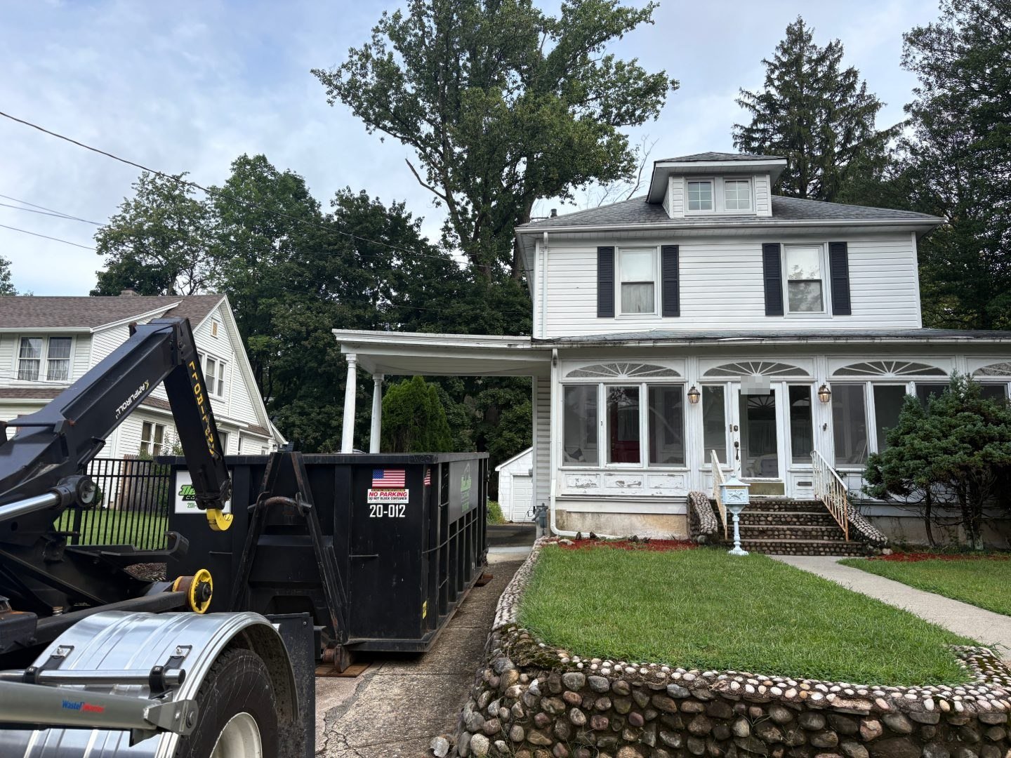 20-yard dumpster being set in a Hillsdale, NJ driveway from the roll-off truck.
