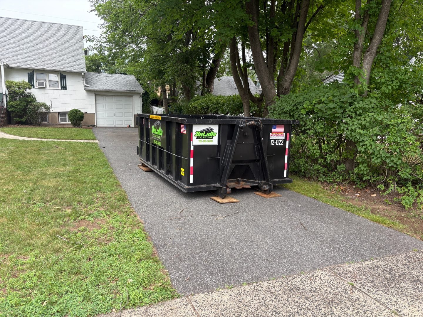 12-yard dumpster on protection boards in a one-car driveway in New Milford, NJ.