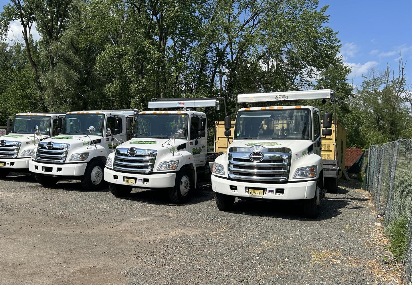 Four DeLalla Carting roll-off trucks lined up in the yard